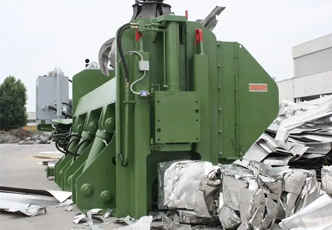 Grüne Idromec Schrottpresse in Recyclinganlage verdichtet leichten Metallschrott zu dichten und festen Paketen