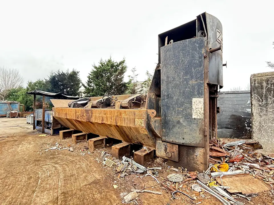 Full side view of the used Zato Blue Whale scrap shear press in a metal scrap yard.